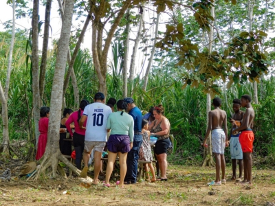 A group of visitors and locals gathering for a traditional Belizean meal in a lush jungle setting during a guided tour from Hopkins and Placencia